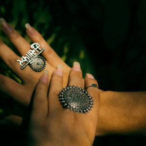 Elegant female hands adorned with intricate oxidized silver rings and jewelry.
