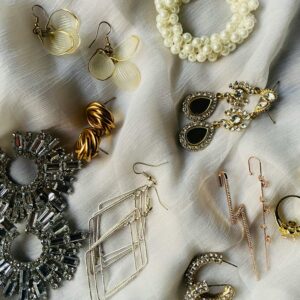 A stylish display of various earrings and jewelry pieces on a white fabric background.